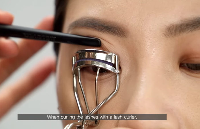 El paso 6 del maquillaje de ojos con capucha es usar un rizador de pestañas