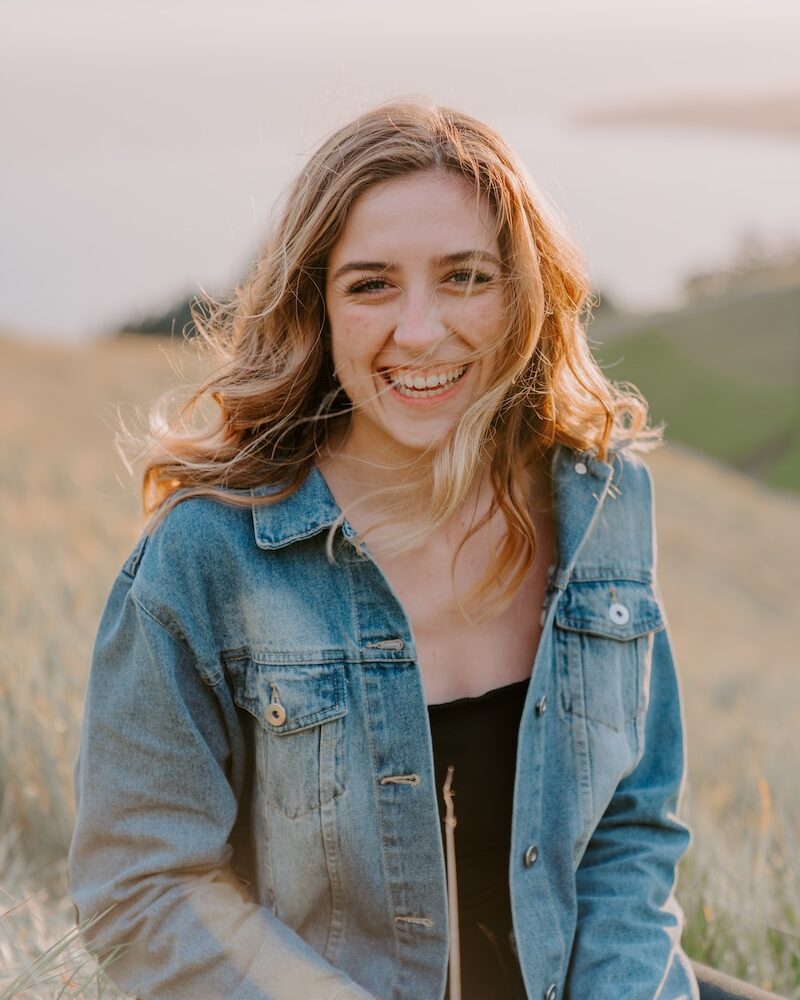 smiling woman sitting on grass during daytime