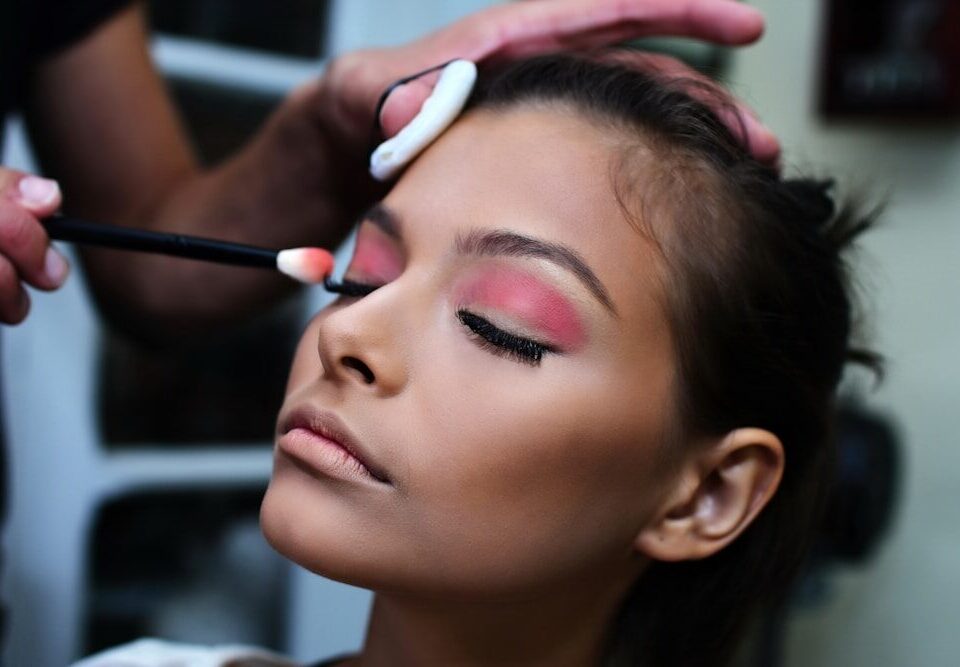 woman with pink lipstick holding white and purple toothbrush